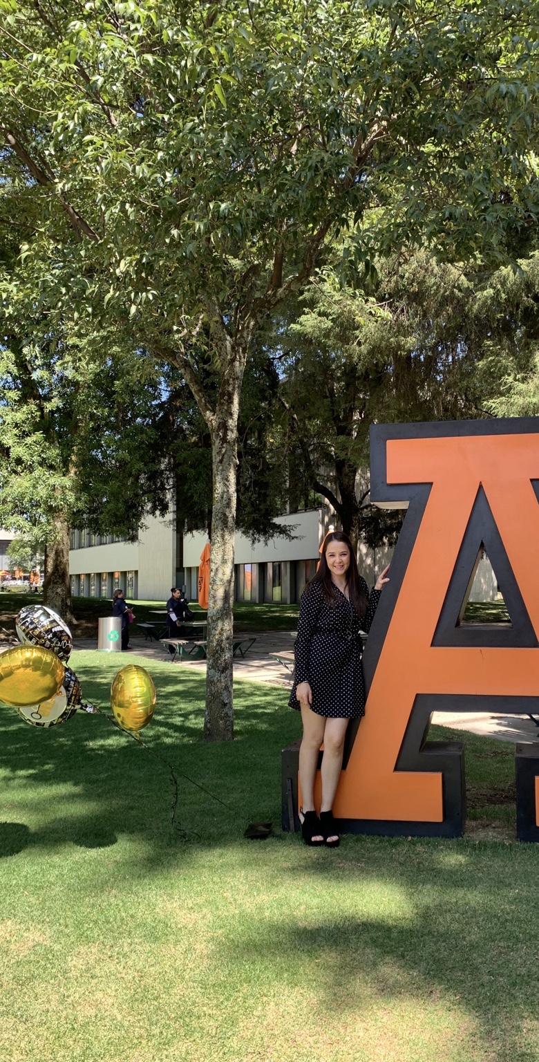 Lizi Osorio junto al emblema de la Universidad Anáhuac en el campus