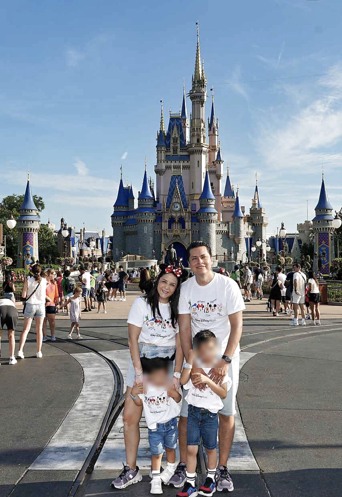 Lizi y su familia frente al castillo de Walt Disney World, con los rostros de sus hijos difuminados