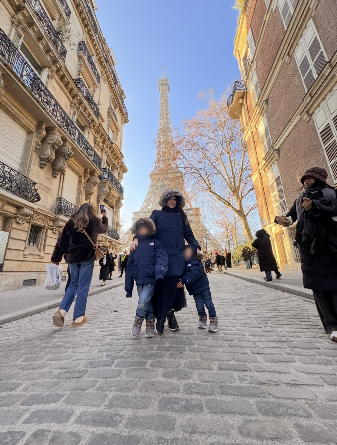 Lizi y sus hijos en París junto a la Torre Eiffel, con los rostros de los niños cubiertos